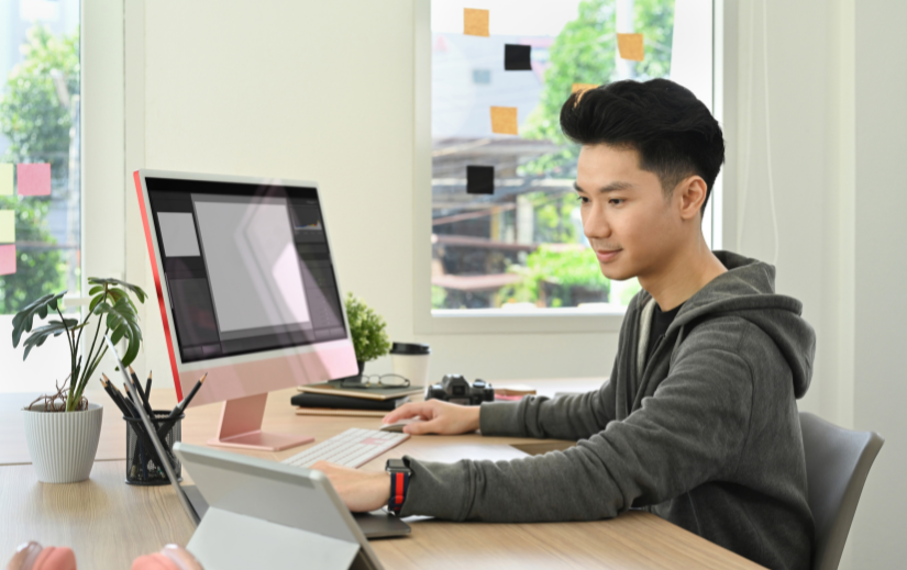 Man working on video editing side hustles at a desktop computer in a bright, modern workspace.